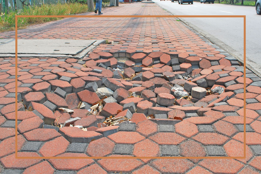 Damaged sidewalk representing a common premises liability hazard